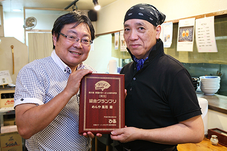 究極のラーメンAWARD選考委員長の沖山氏(写真左)から、「めんや風花」店主の植村さん(右)に記念の盾が手渡された。