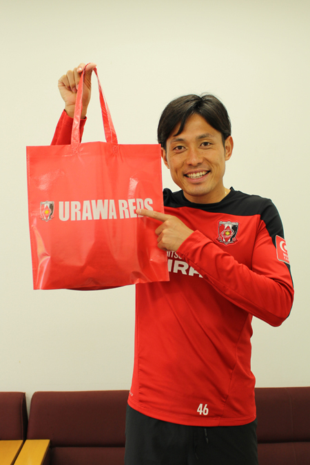 11月22日(土)・ガンバ大阪戦で来場者全員にプレゼントされるオリジナルトートバッグを手にする森脇良太(浦和レッズ)　(c)URAWA REDS